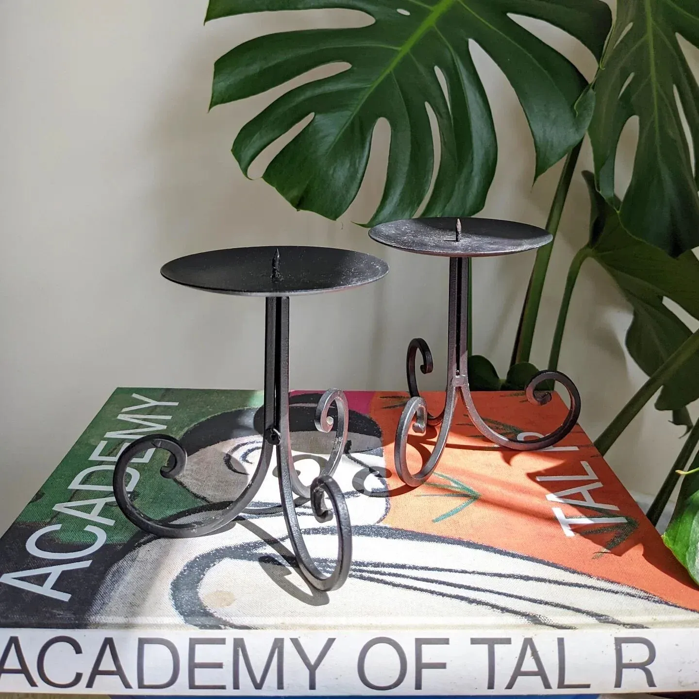 Curls get the candles. Pair of candle stick holders. Base is a tripod of curly, scrolled black metal